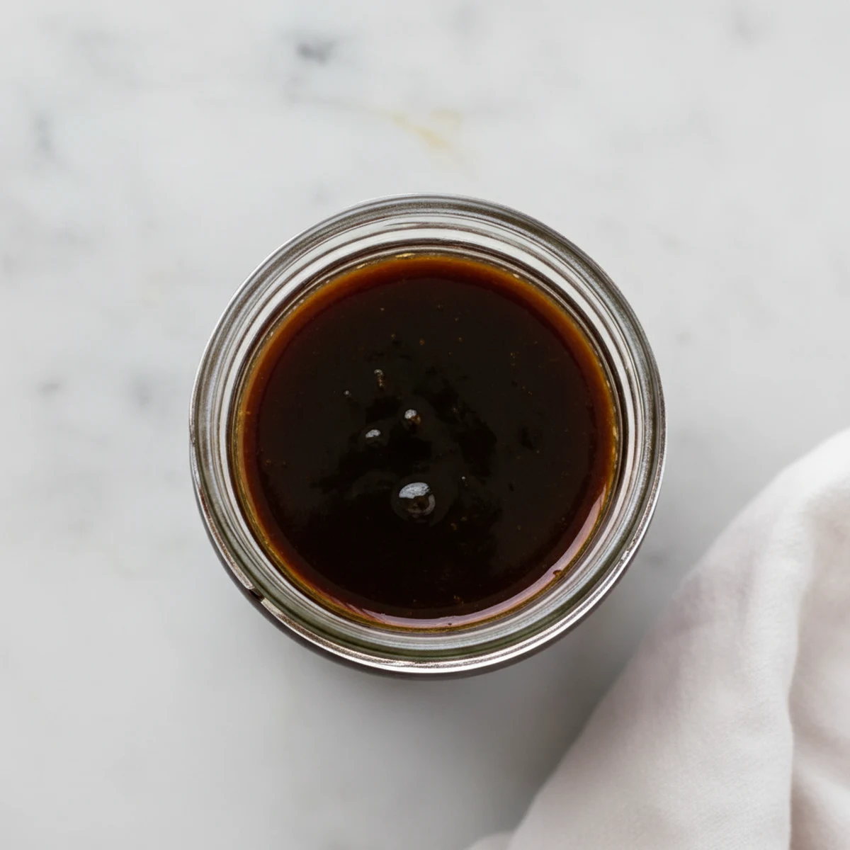 Finished sweet soy glaze (eel sauce) in a plain glass jar.